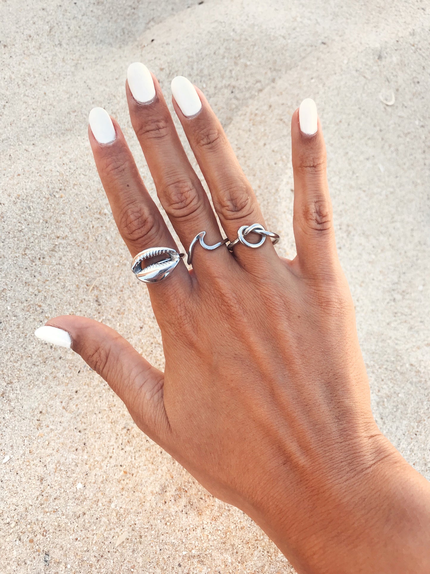 Vista da mão com o Anel prateado com búzio em aço inoxidável no dedo.
