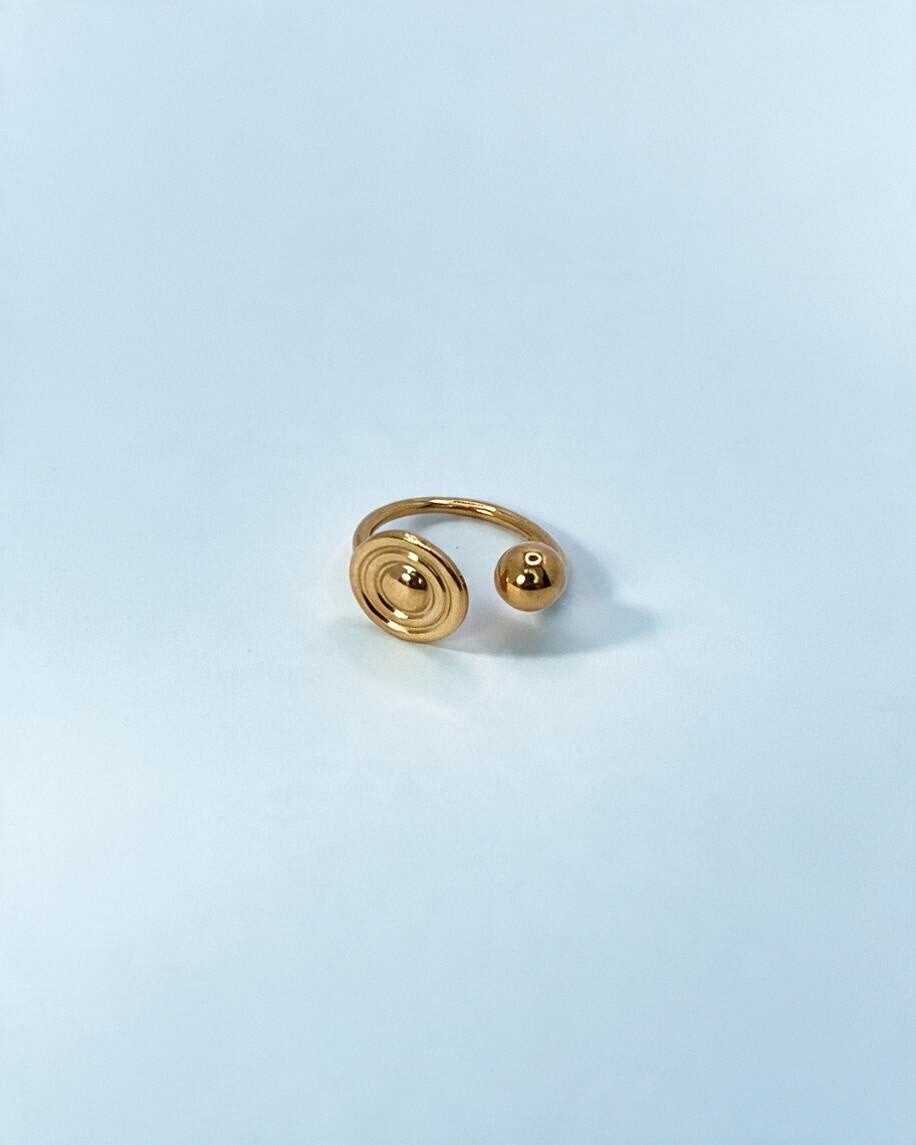Anel Órbita dourado visto de cima em ângulo, com o aro fino atrás do disco de círculos concêntricos e da esfera.