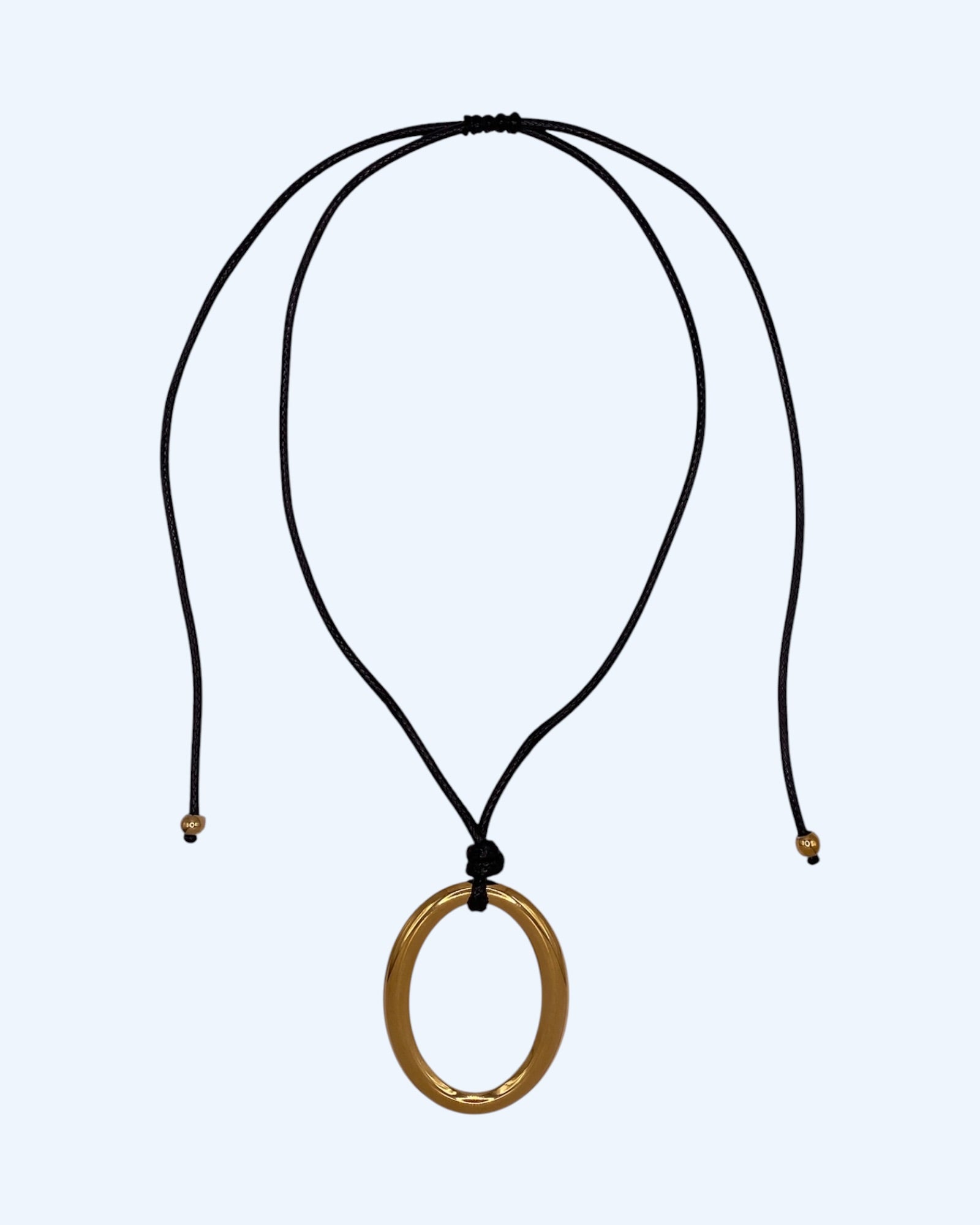Colar ajustável em choker com medalhão oval dourado em aço inoxidável e cordão preto. Colar versátil, contemporâneo e minimalista