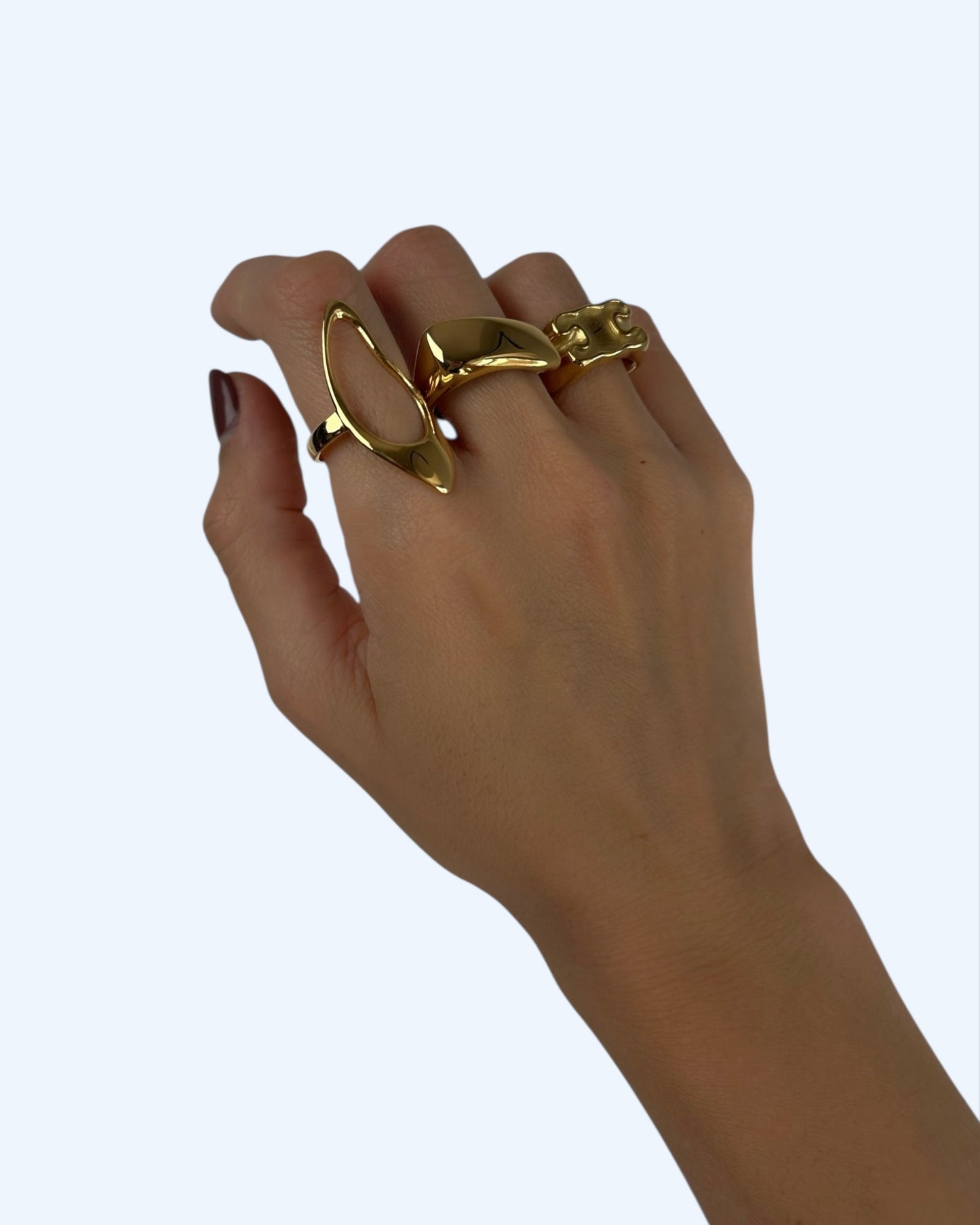 Anel ajustável em aço inoxidável com linhas recortadas e curvas orgânicas dourado a ser usado num styling com outros dois anéis.