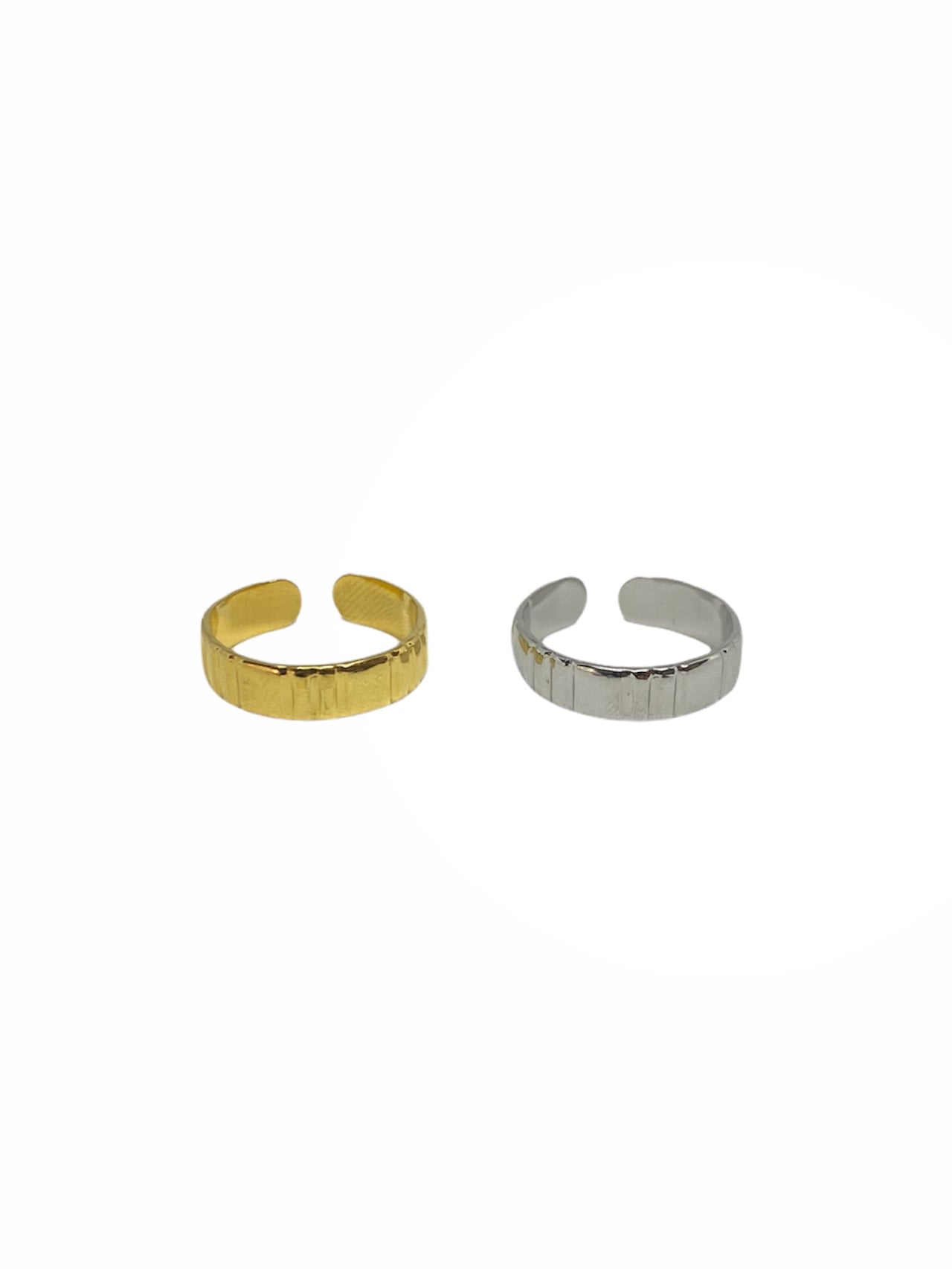 Vista frontal do anel dourado e do anel prateado em forma de aliança com riscas vincadas ajustável em aço inoxidável.
