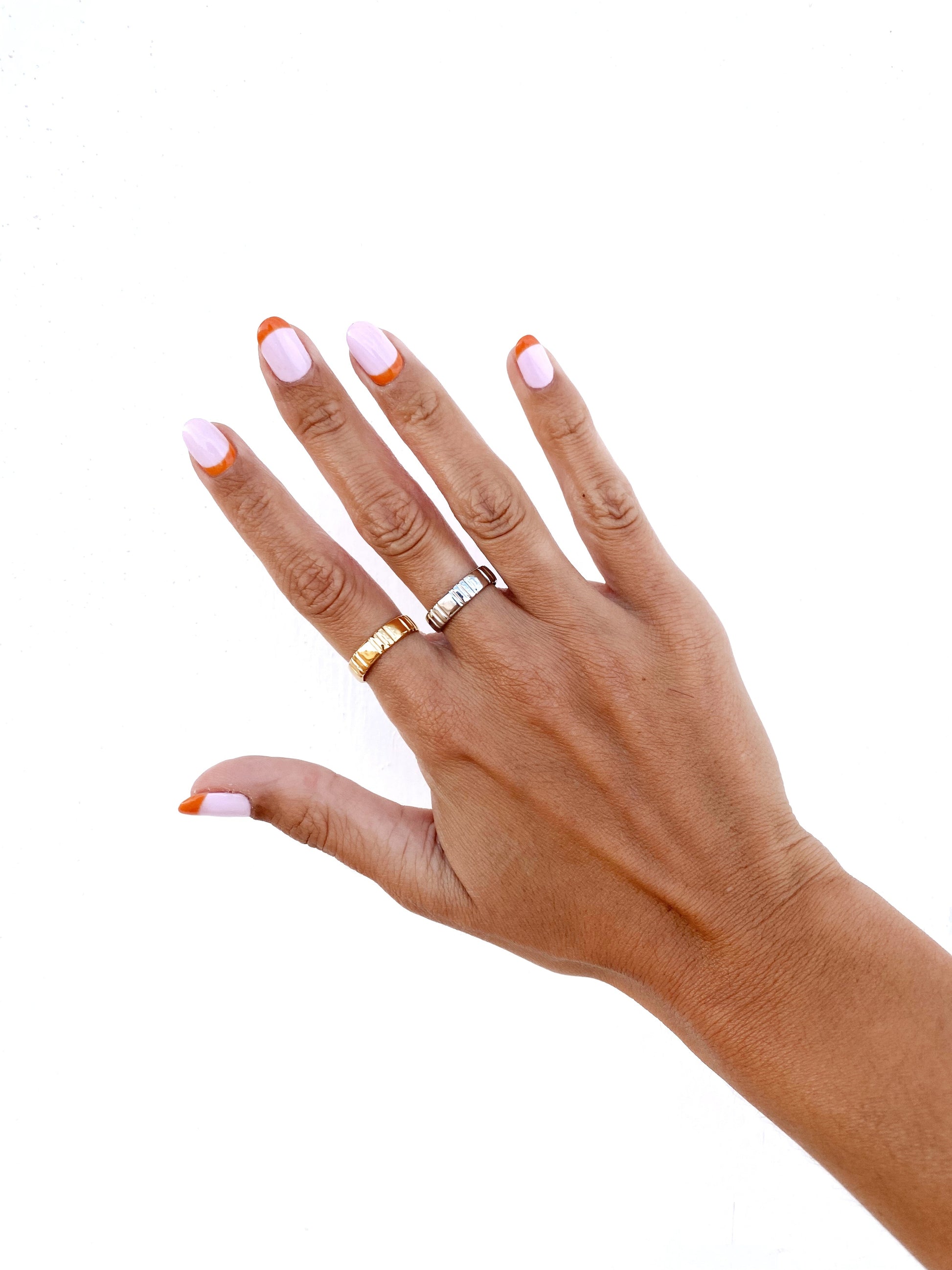 Vista a serem usados na mão, do anel dourado e do anel prateado em forma de aliança com riscas vincadas ajustável em aço inoxidável.