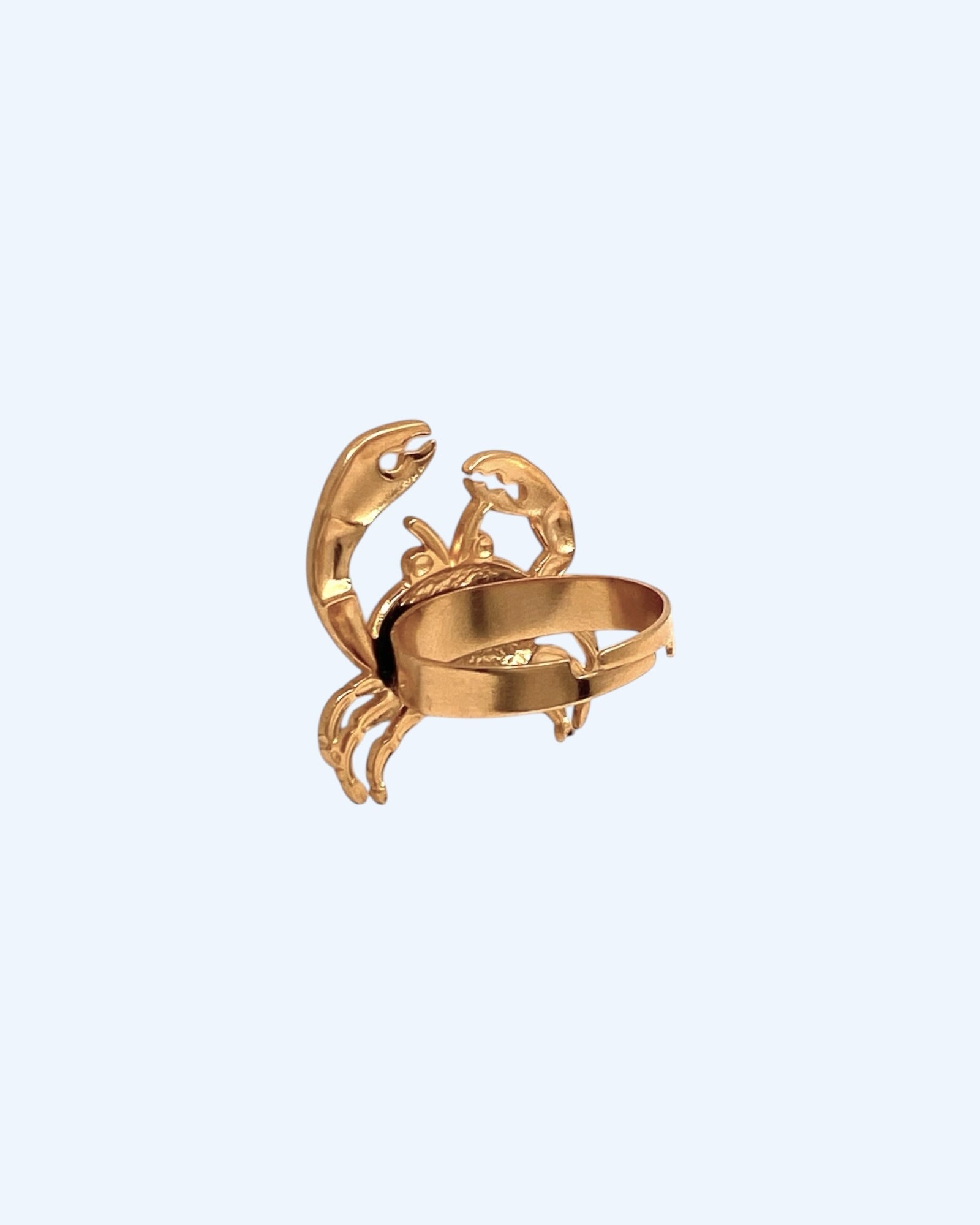 Vista lateral do Anel dourado ajustável em aço inoxidável com forma de caranguejo. Um anel resistente à água, para ser usado em looks de verão, looks casuais e de festa. Um anel divertido de inspiração no mar e no verão.