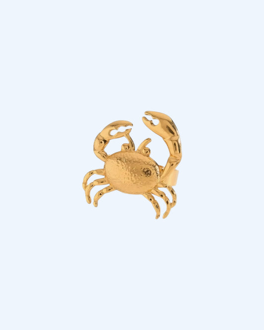 Vista frontal do Anel dourado ajustável em aço inoxidável com forma de caranguejo. Um anel resistente à água, para ser usado em looks de verão, looks casuais e de festa. Um anel divertido de inspiração no mar e no verão.