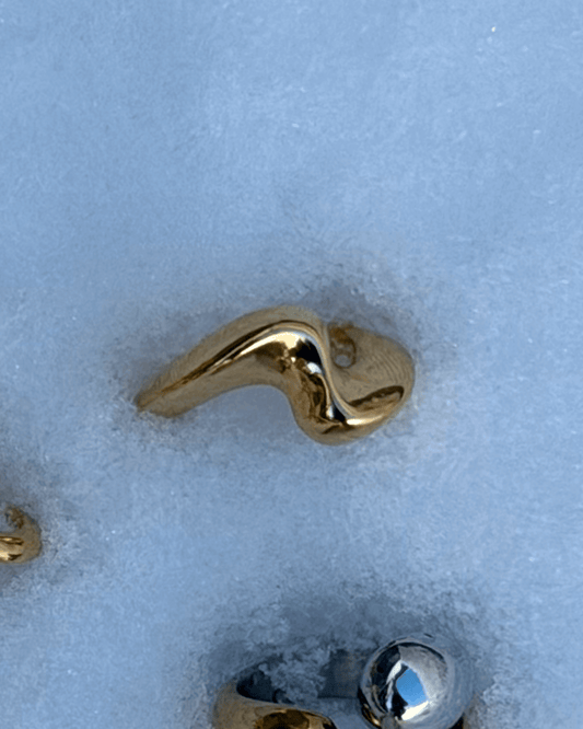 Vista frontal do anel chunky minimal dourado  com design ondulado e fluido em aço inoxidável.