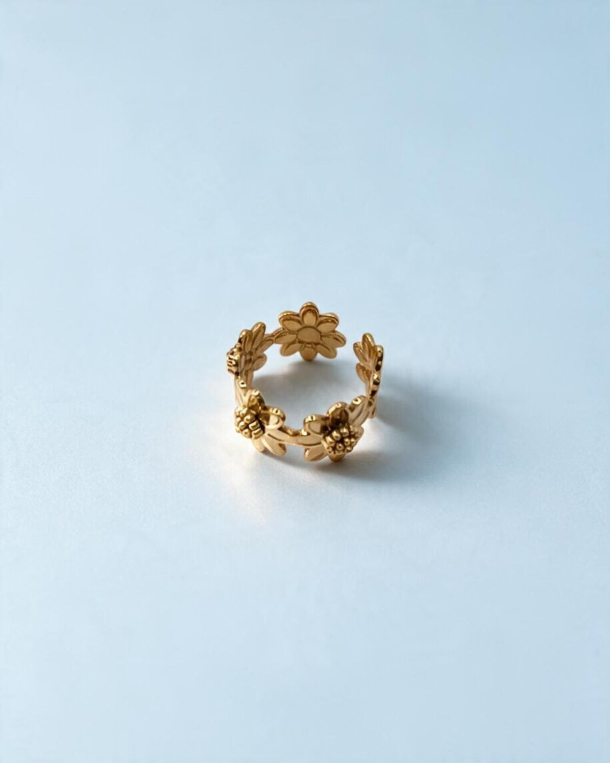 Anel dourado de flores visto de cima, mostrando o interior do aro e a disposição das flores à sua volta.