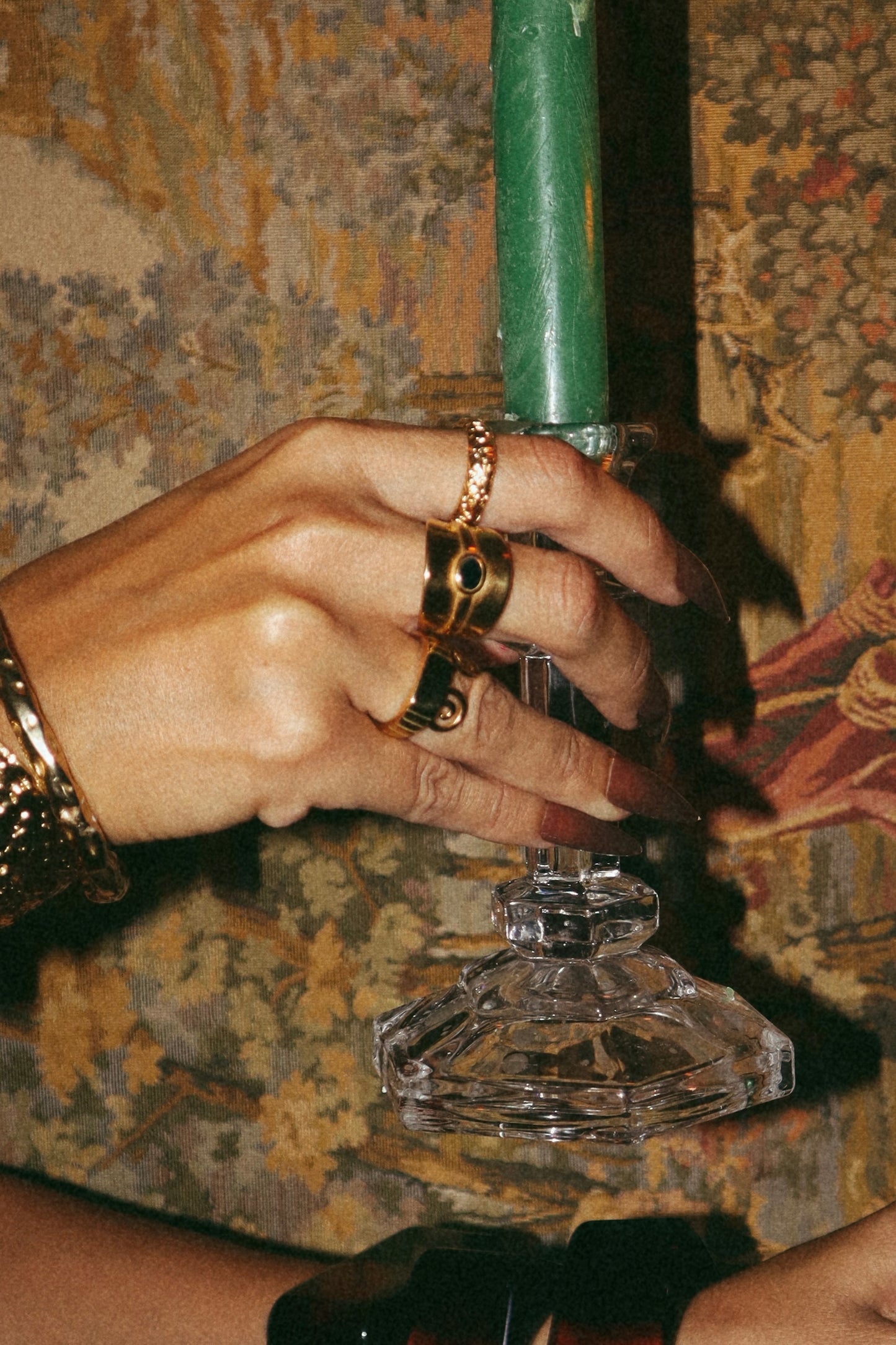 Anel largo dourado em aço inoxidável com uma pedra central preta. Vista na mão.