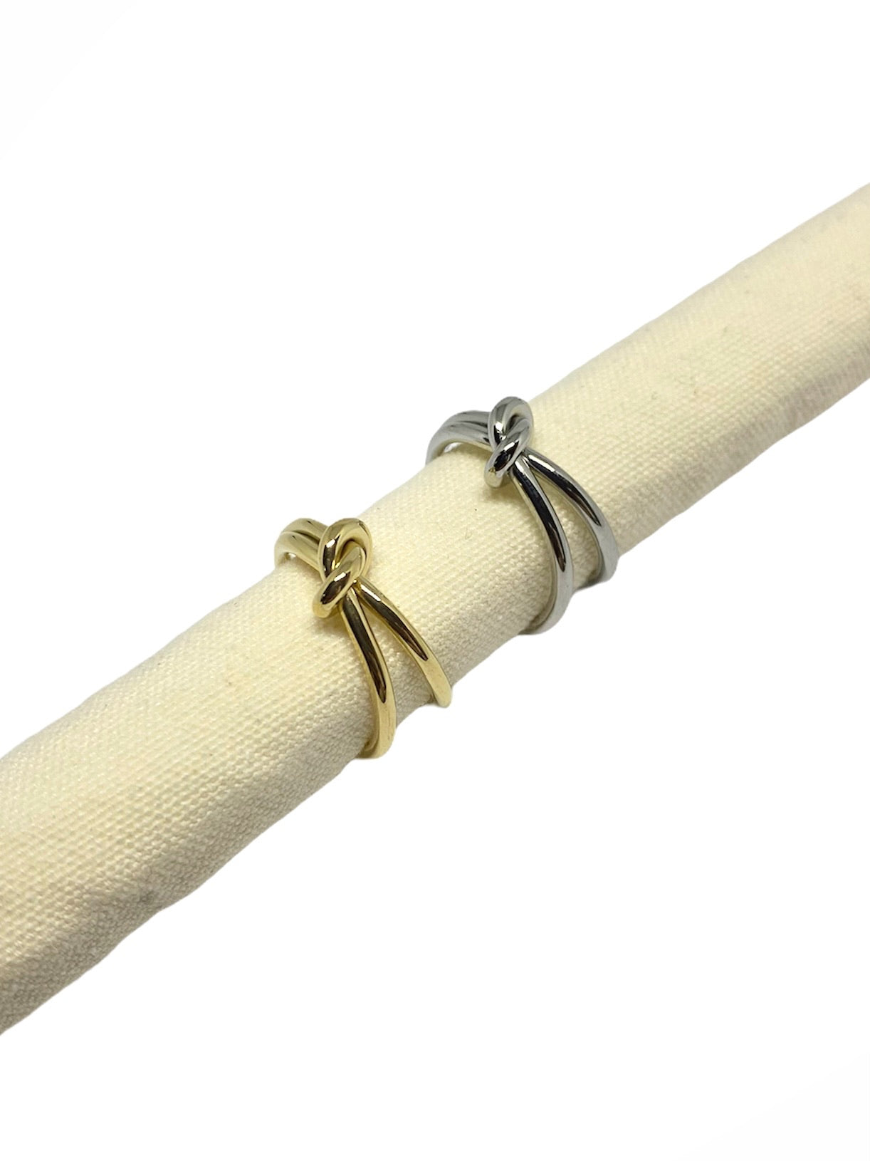 Vista lateral do Anel duplo com nó prateado em aço inoxidável e do Anel duplo com nó dourado em aço inoxidável.