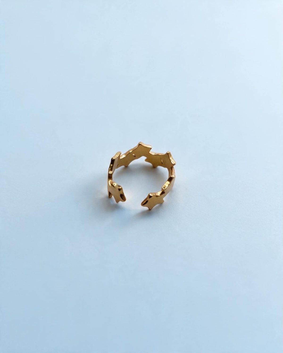  Anel de estrelas dourado ajustável visto de cima, com a abertura entre as extremidades em destaque.