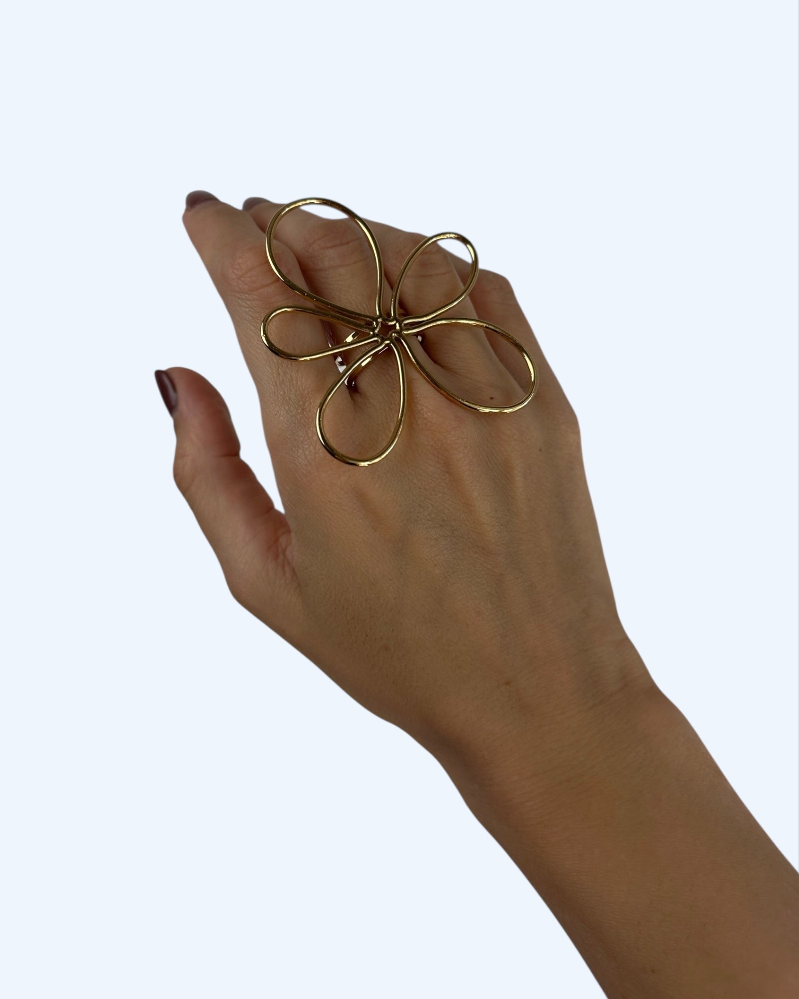 Vista a ser usado na mão do anel ajustável dourado com flor maxi em aço inoxidável. É um anel romântico, Artístico, leve e impactante.
