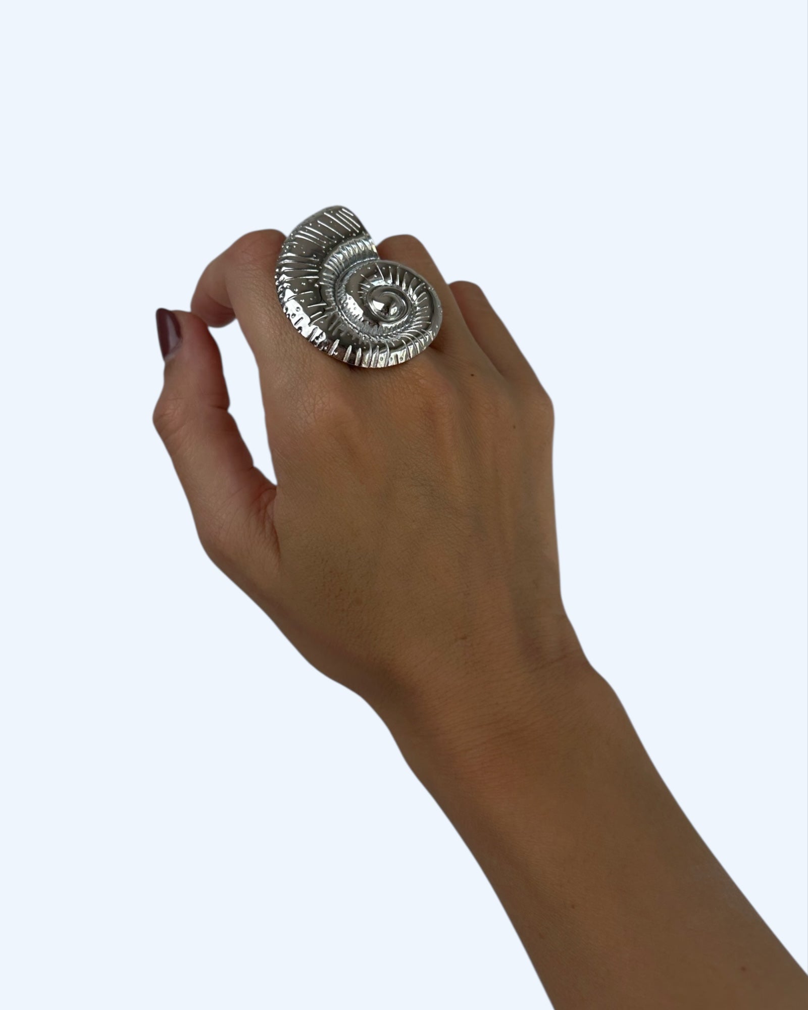 Vista a ser usado na mão do anel com búzio grande em aço inoxidável ajustável prateado. Este anel é oversized e tem um caracol do mar gigante. É um anel bold e edgy.