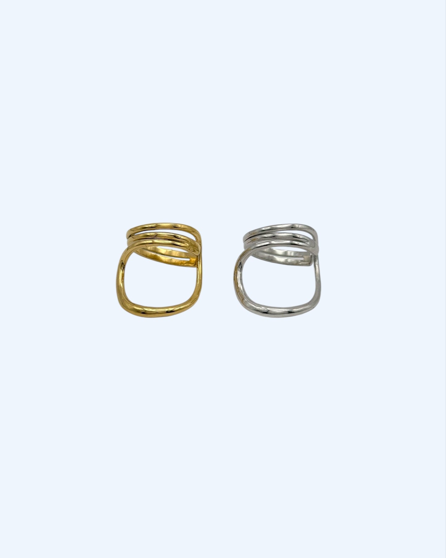 Vista frontal do anel minimalista que contorna o dedo dourado em aço inoxidável e do anel minimalista que contorna o dedo prateado em aço inoxidável. São simultaneamente clean e bold.
