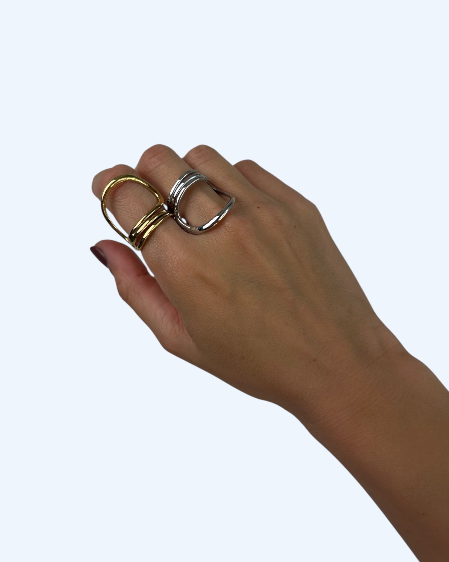 A anel minimalista que contorna o dedo dourado em aço inoxidável e anel minimalista que contorna o dedo prateado em aço inoxidável a serem usados em conjunto na mão.