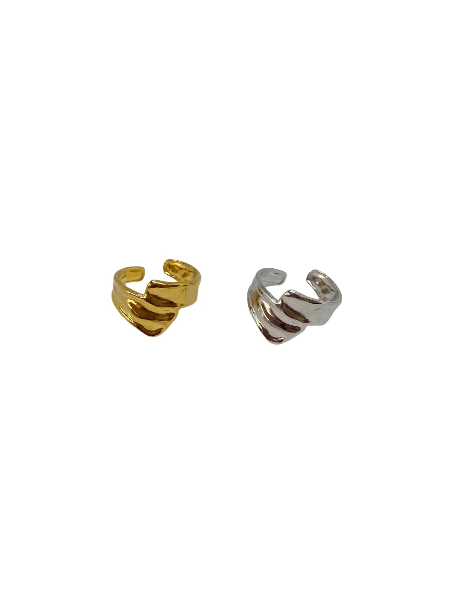 Vista lateral do anel dourado minimalista com duas tiras com textura orgânica que cruzam à frente e do anel prateado minimalista com duas tiras com textura orgânica que cruzam à frente.