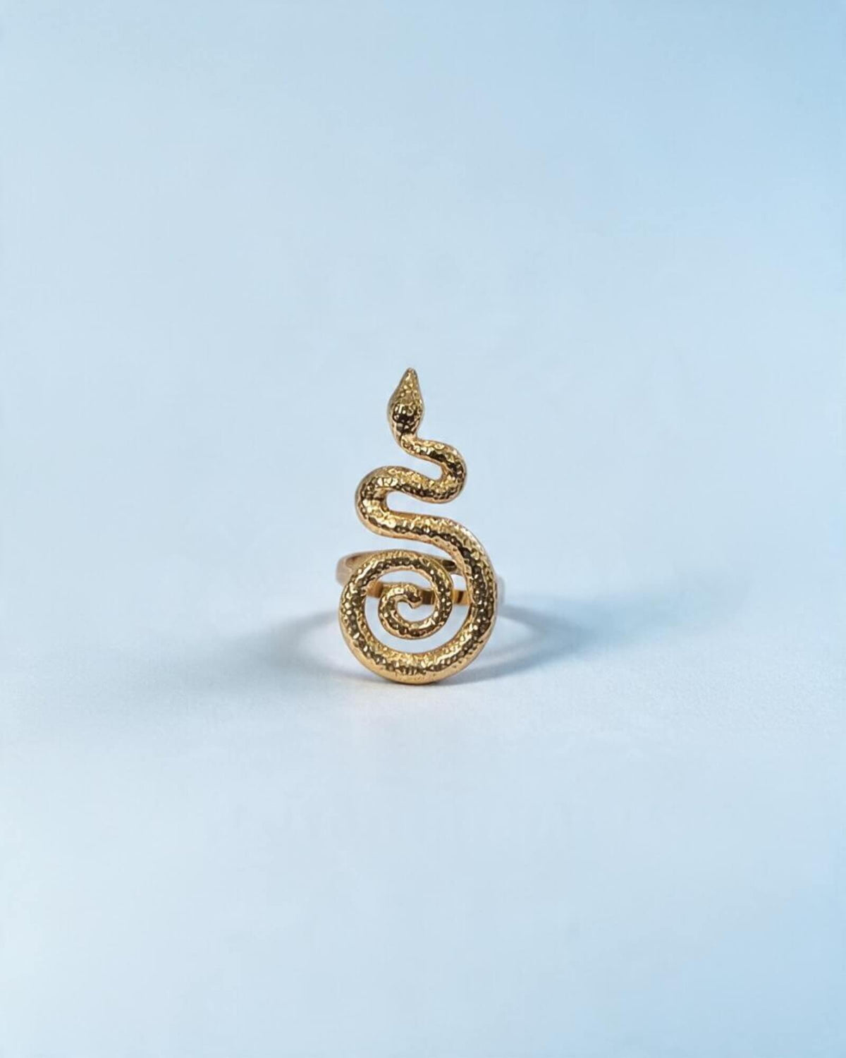Vista frontal do anel serpente dourado, com cabeça elevada, corpo ondulado e cauda enrolada em espiral.