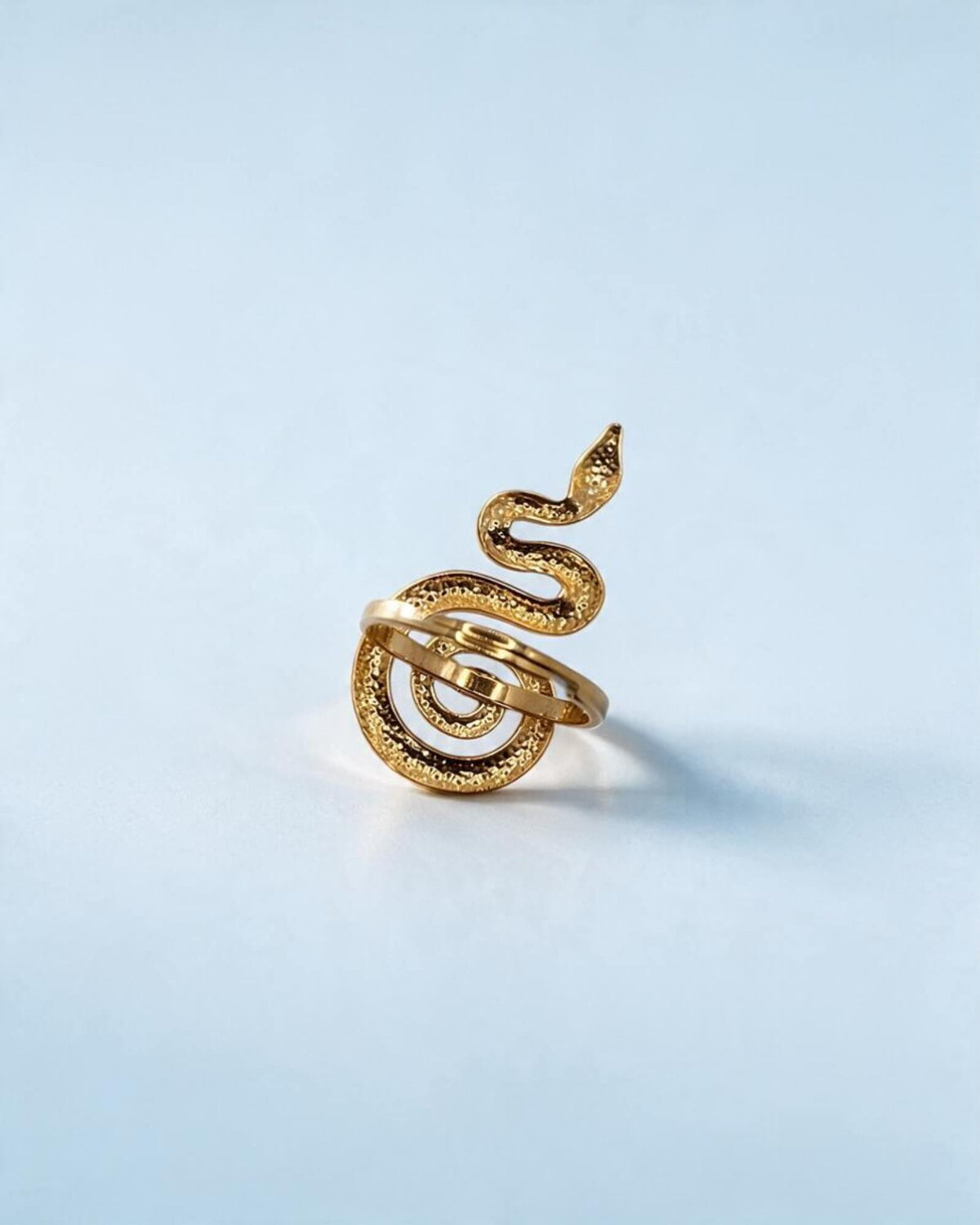 Vista posterior do anel serpente dourado, com o aro em primeiro plano e a textura do corpo e da espiral visível.