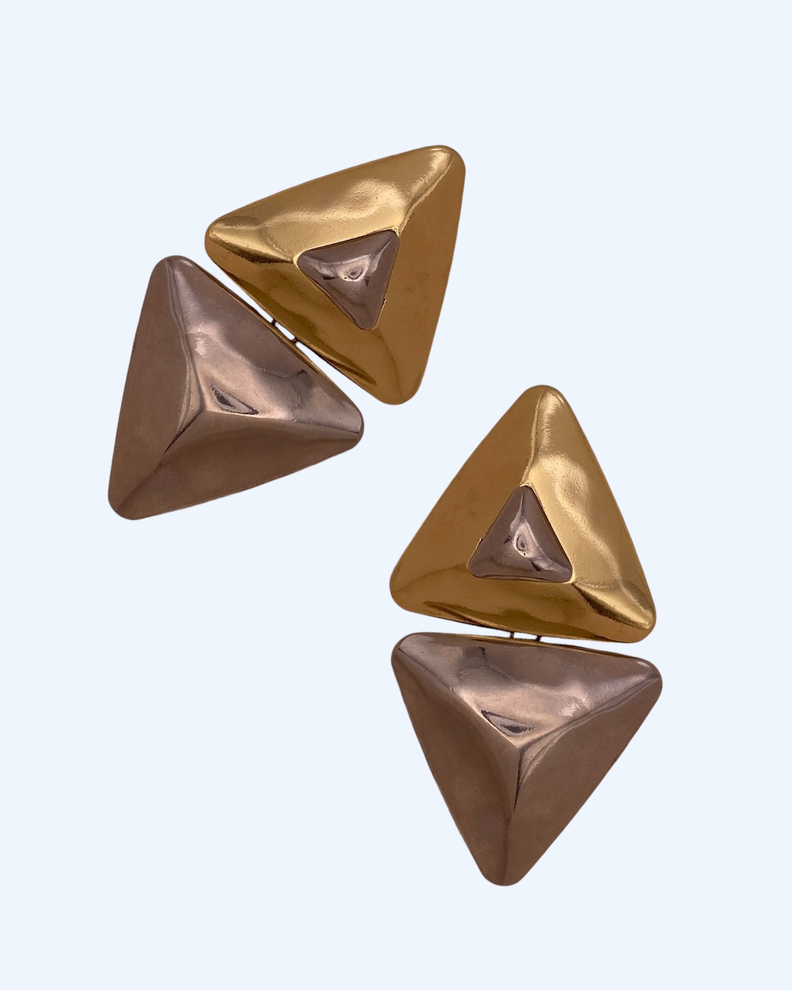 Vista lateral dos brincos geométricos triangulares em metal dourado e prateado. Brincos leves, contemporâneos, para o dia à dia e para festas.