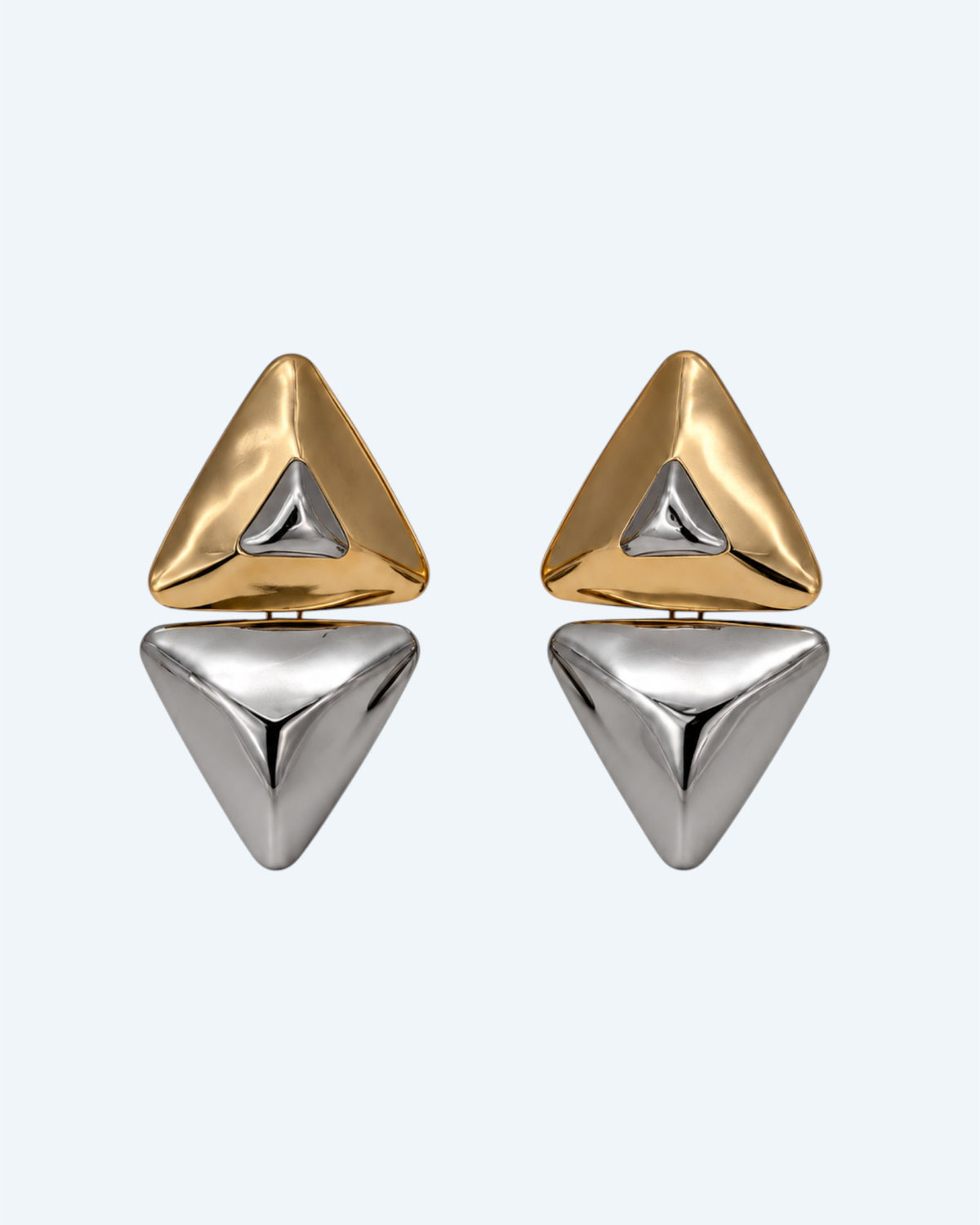 Vista frontal dos brincos geométricos triangulares em metal dourado e prateado. Brincos leves, contemporâneos, para o dia à dia e para festas.