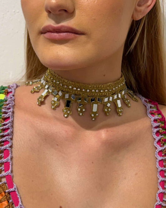 Vista diferente de detalhe da modelo a usar o choker dourado em faixa de tecido com espelhos e brilhantes Mirage.