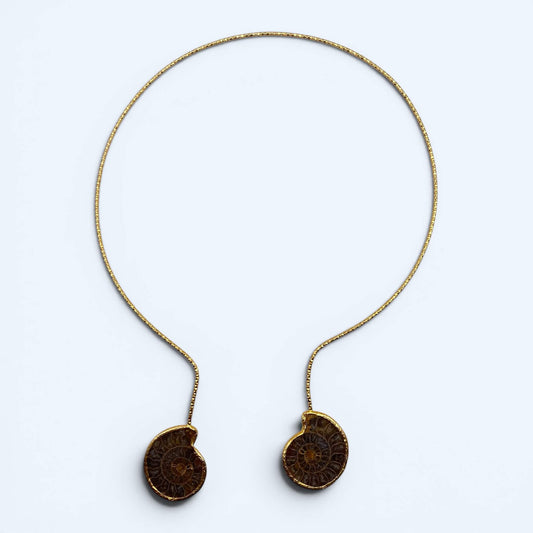 Vista frontal do Colar dourado aberto com amonites. De inspiração orgânica com fósseis e acabamento texturizado, é a gargantilha perfeita para cerimónias, festivais, festas de verão e looks mais glamorosos.