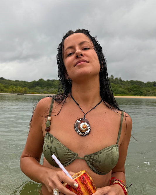 Vista da modelo a usar o colar com búzio espiral grande feito à mão. É um colar para looks de verão.