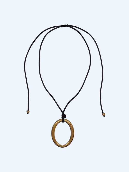 Colar ajustável em choker com medalhão oval dourado em aço inoxidável e cordão preto. Colar versátil, contemporâneo e minimalista.