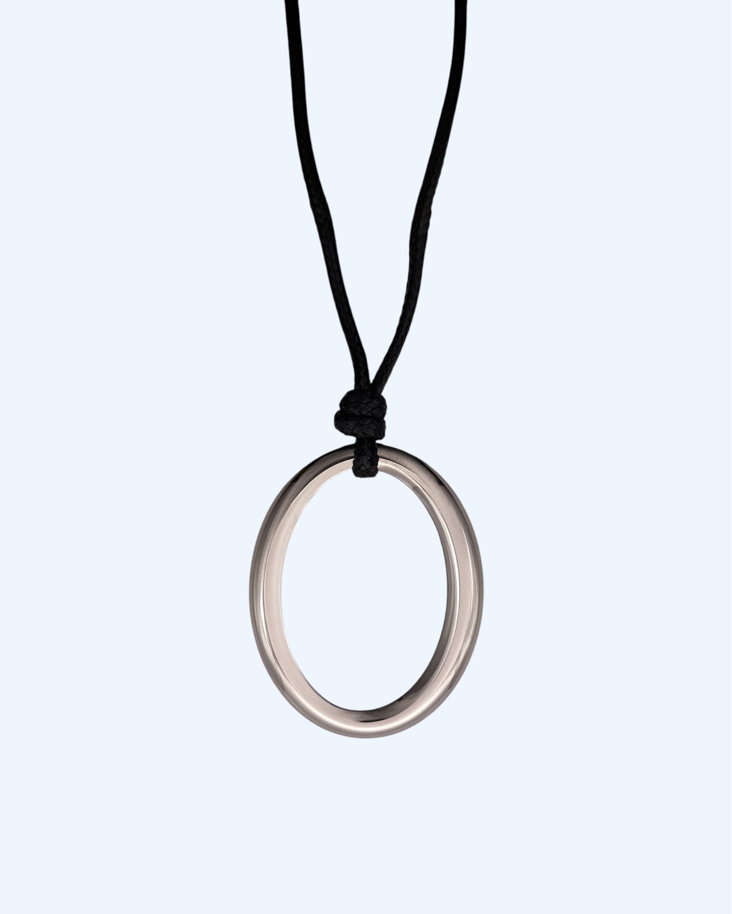 Detalhe do medalhão oval prateado em aço inoxidável e do cordão preto ajustável de colar minimalista feminino.  Colar versátil, contemporâneo e minimalista.
