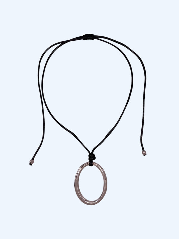 Colar ajustável em choker com medalhão oval prateado em aço inoxidável e cordão preto. Colar versátil, contemporâneo e minimalista.