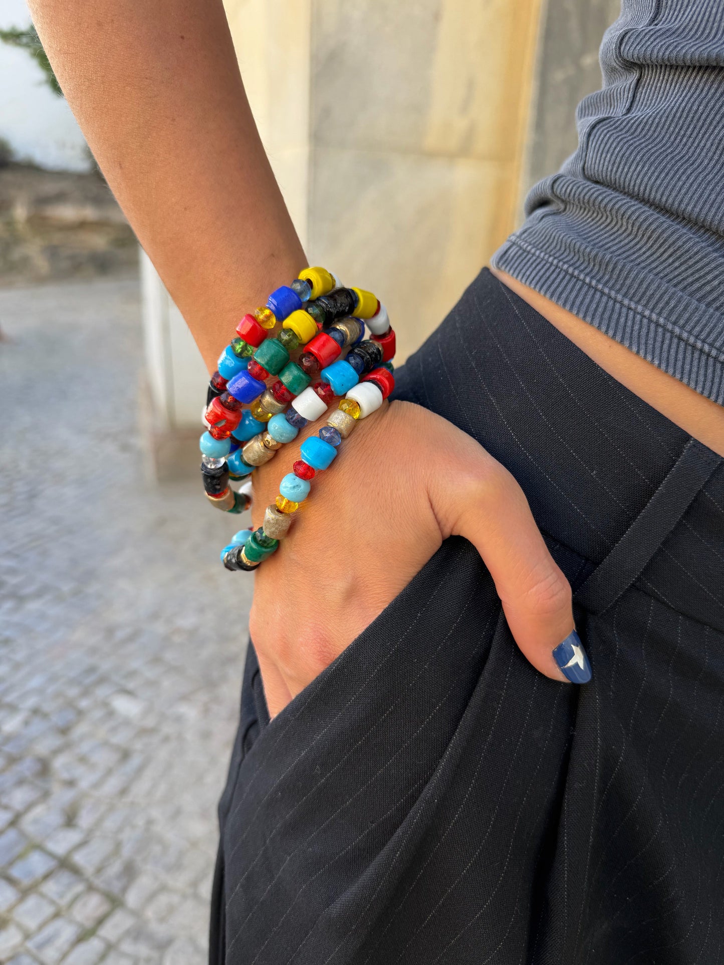 Detalhe do colar de verão comprido colorido artesanal com missangas de cerâmica e resina em tons vibrantes, a ser usado como pulseira de várias voltas.