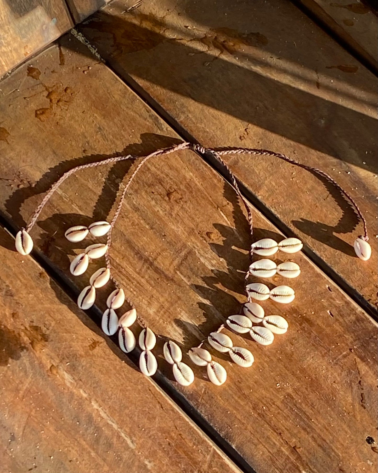 Colar com búzios cauri naturais em cordão entrançado castanho ajustável. Este colar surfer é um colar de búzios para usar em festas, festivais e dias de verão. Colar boho casual que ajusta como gargantilha de búzios ou colar comprido de búzios.