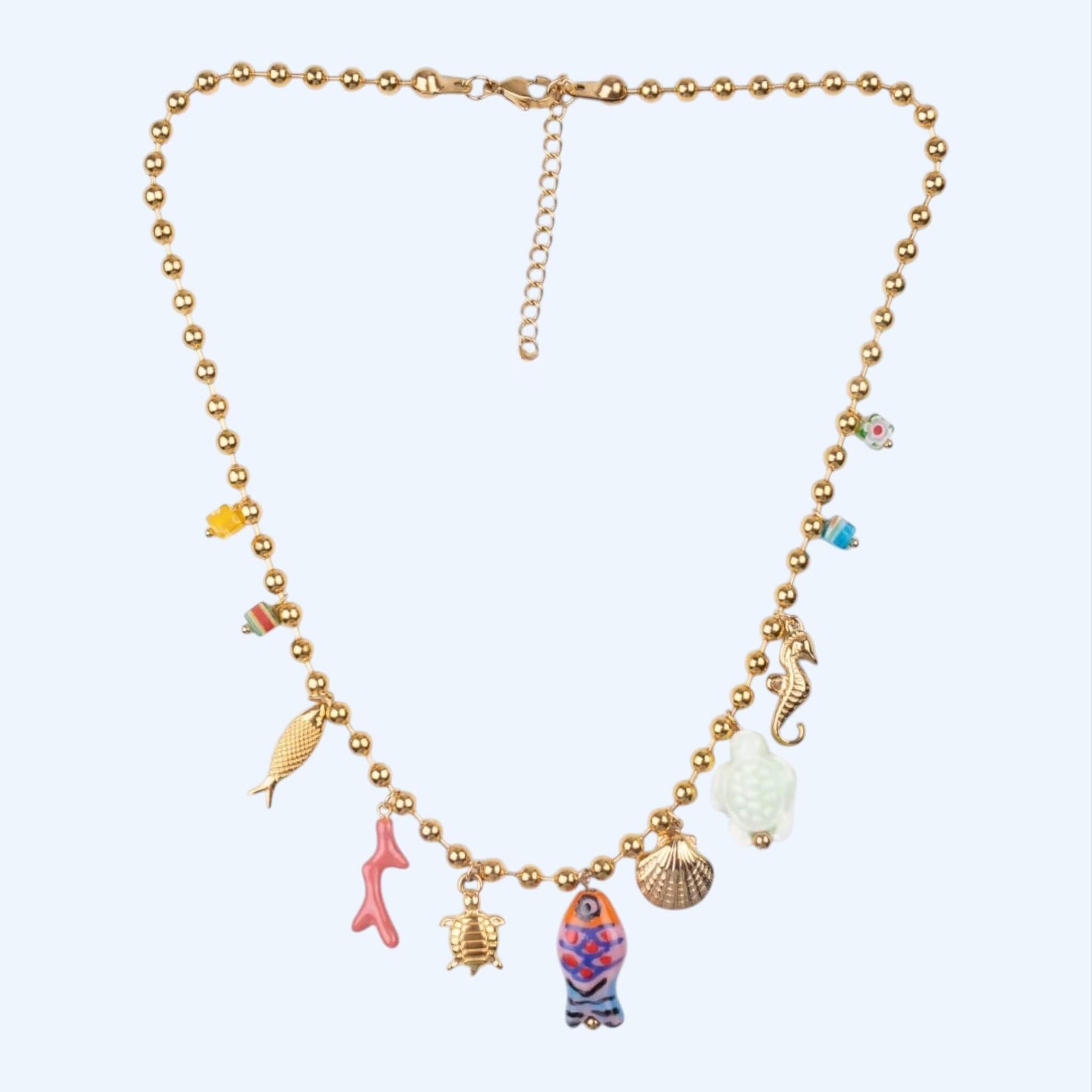 Vista frontal do Colar dourado em aço inoxidável em corrente de inspiração no oceano, com pendentes de peixe, concha, coral, tartaruga, cavalo-marinho e contas coloridas. Este colar tem vibe beachy, fun e descontração. É um colar dourado com cores, perfeito para o verão.