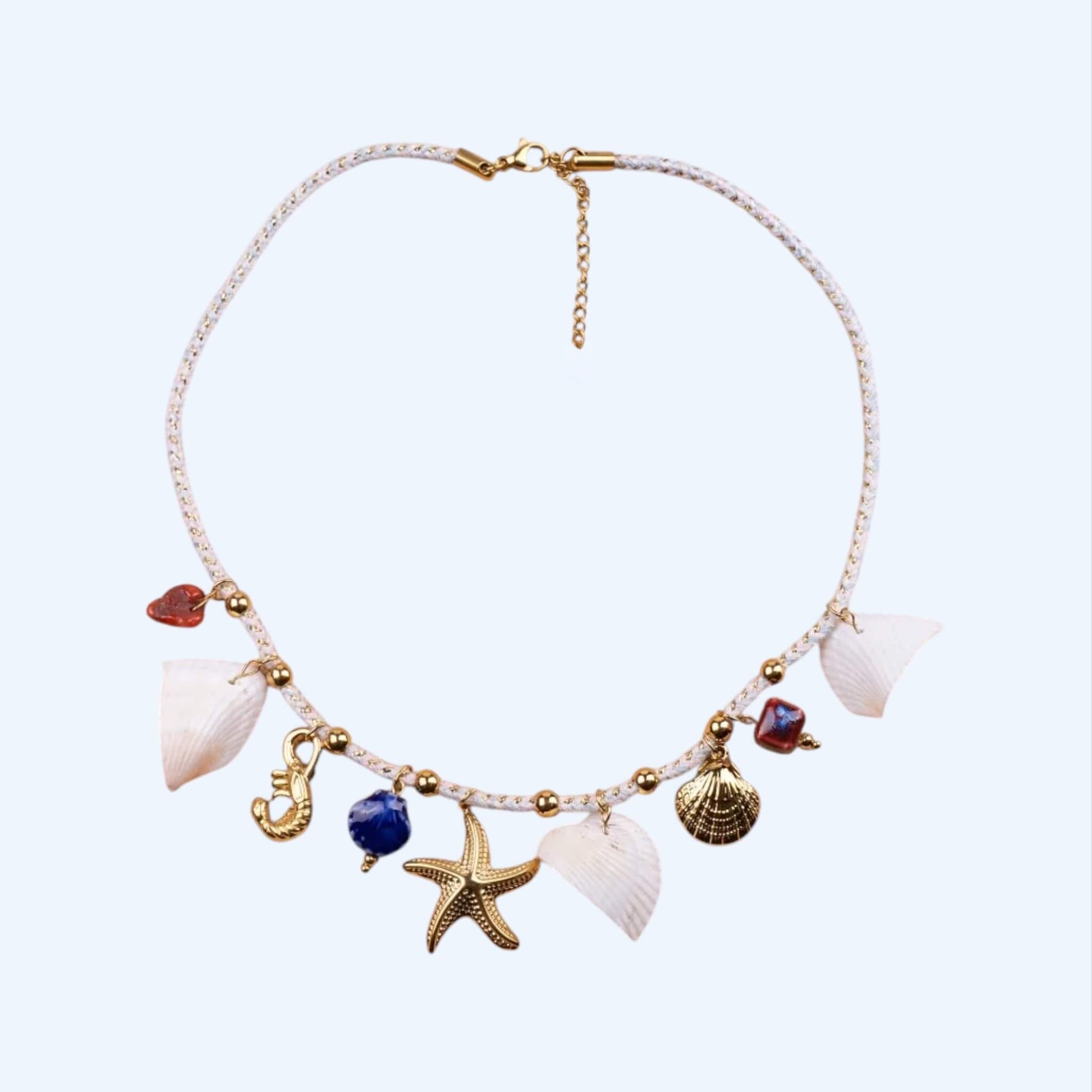 Vista frontal do Colar em cordão branco entrançado em detalhes dourados, misturado com conchas naturais, pendentes coloridos em cerâmica e pendentes em aço inoxidável em forma de estrela do mar, de concha e de camarão.
Este é um colar com inspiração marinha, de estilo boho e coastal chic.