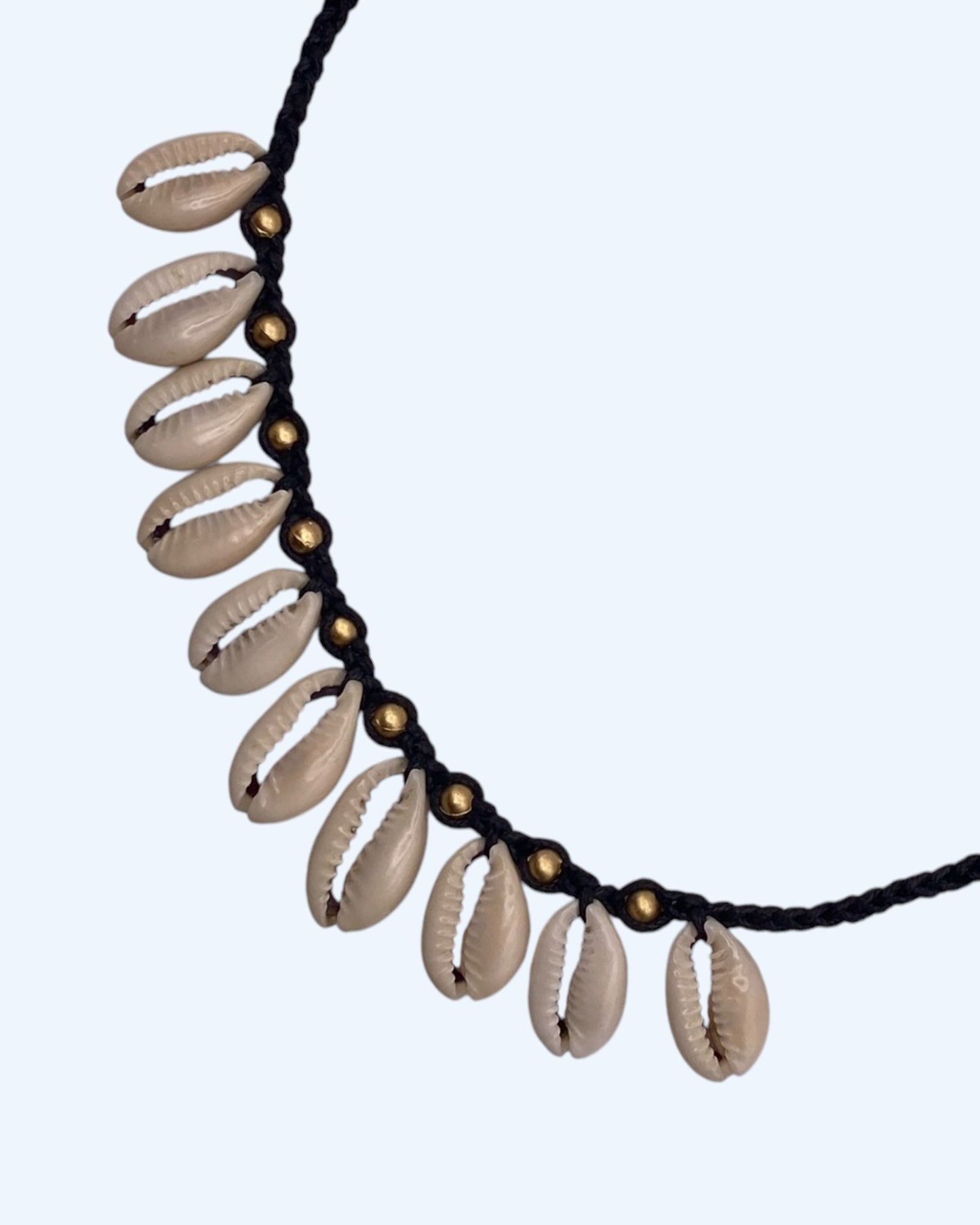 Detalhe de comprimento do Colar surfer com búzios cauri naturais e detalhes dourados em cordão entrançado preto ajustável. Colar de verão, para usar na praia ou na cidade.