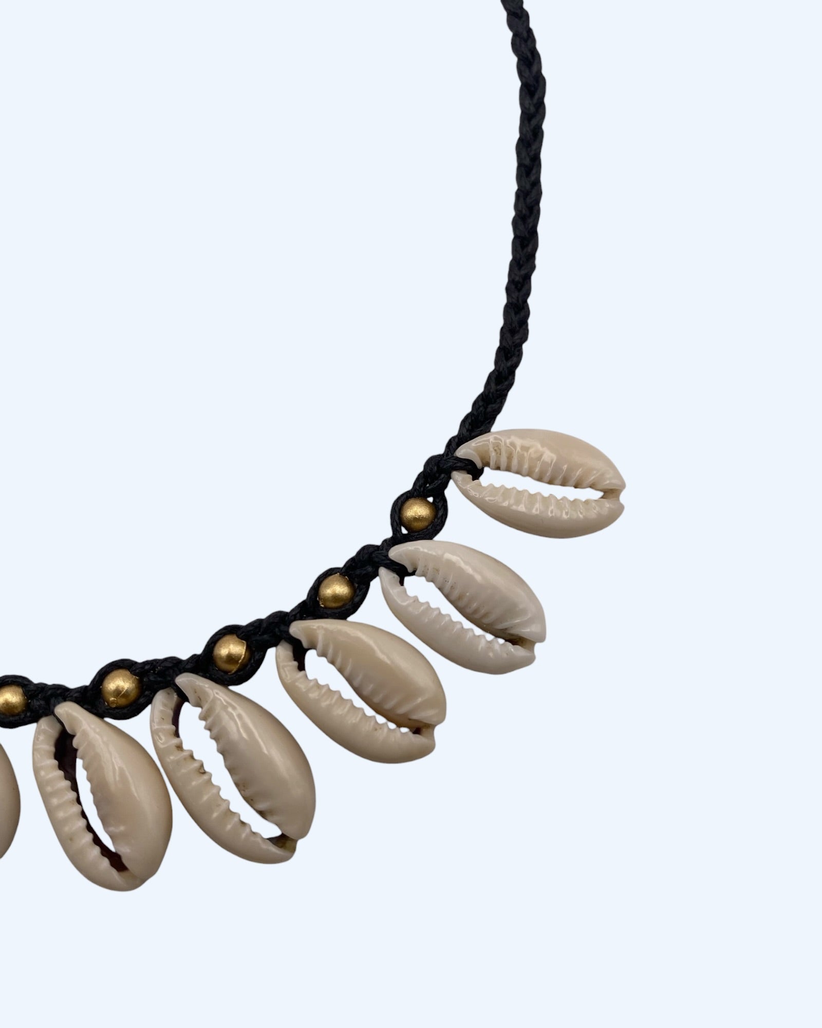 Detalhe de comprimento do Colar surfer com búzios cauri naturais e detalhes dourados em cordão entrançado preto ajustável. Colar de verão, para usar na praia ou na cidade.