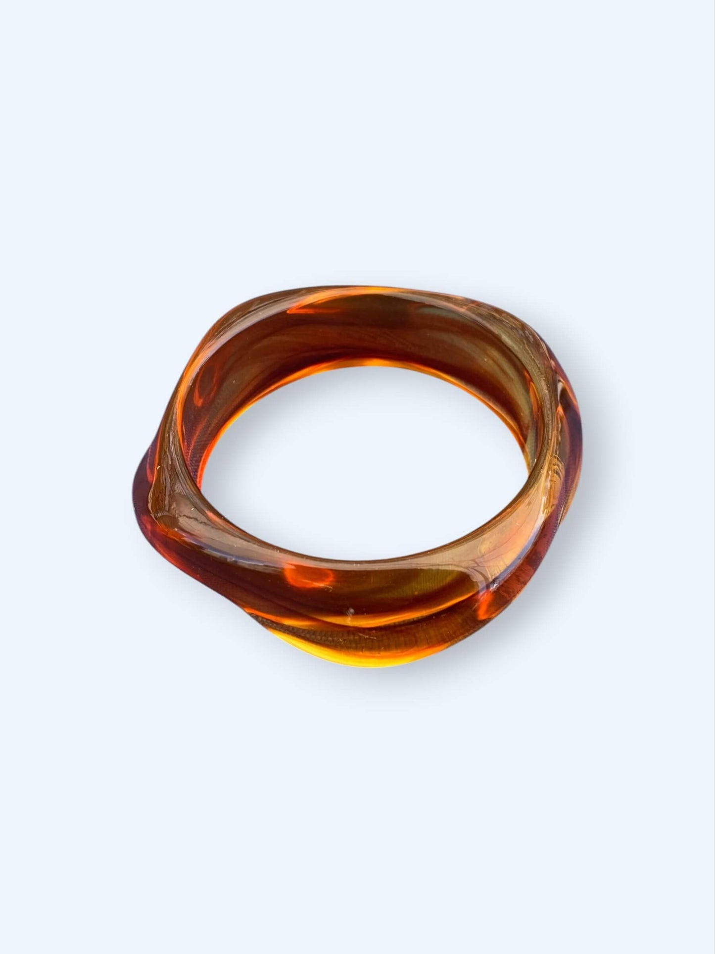 Vista da pulseira âmbar que pertence ao Conjunto de três pulseiras em resina. Estas pulseiras tem acabamento glossy e são dos tons pretos e castanho, são perfeitas para combinar com tudo ou para usar sem nada. São o acessório perfeito para o verão.