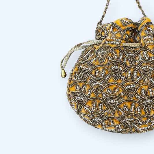 Detalhe da Mala bucket dourada bordada com missangas que combina textura, brilho e um mood boho. O padrão artesanal e o tom dourado são perfeitos para looks de festa e looks de verão. é uma mala boho.