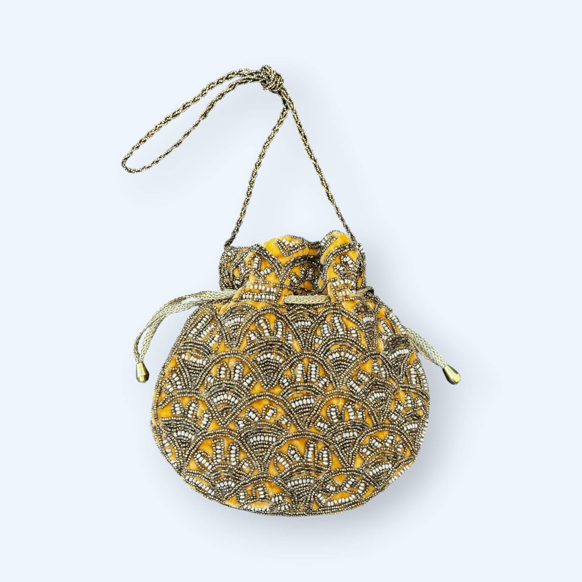 Vista frontal da Mala bucket dourada bordada com missangas que combina textura, brilho e um mood boho. O padrão artesanal e o tom dourado são perfeitos para looks de festa e looks de verão. é uma mala boho.