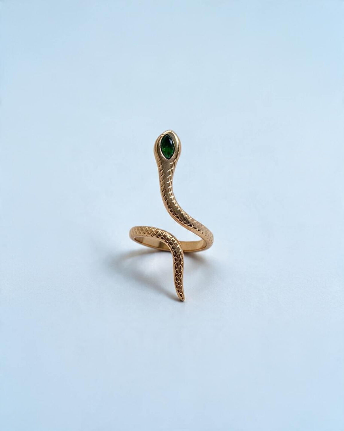 Vista frontal do anel Víbora dourado, com cabeça de serpente elevada, detalhe verde e cauda com textura de escamas.