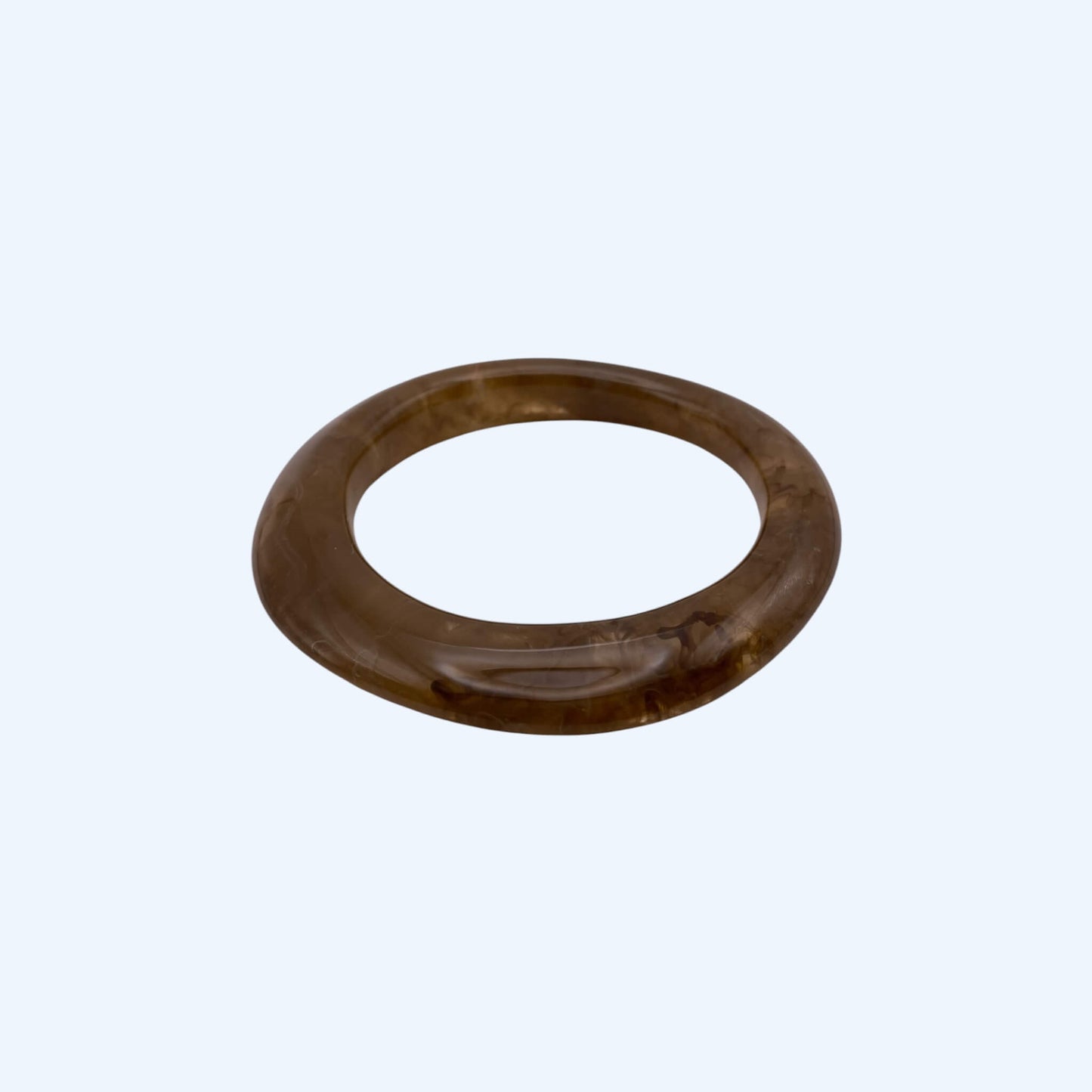 Vista lateral da Pulseira bangle castanha em resina, com acabamento glossy. Pulseira para ser usada sozinha ou em conjunto com outras pulseiras. Pulseira ideal para estilo boho, para estética de verão e da cidade.