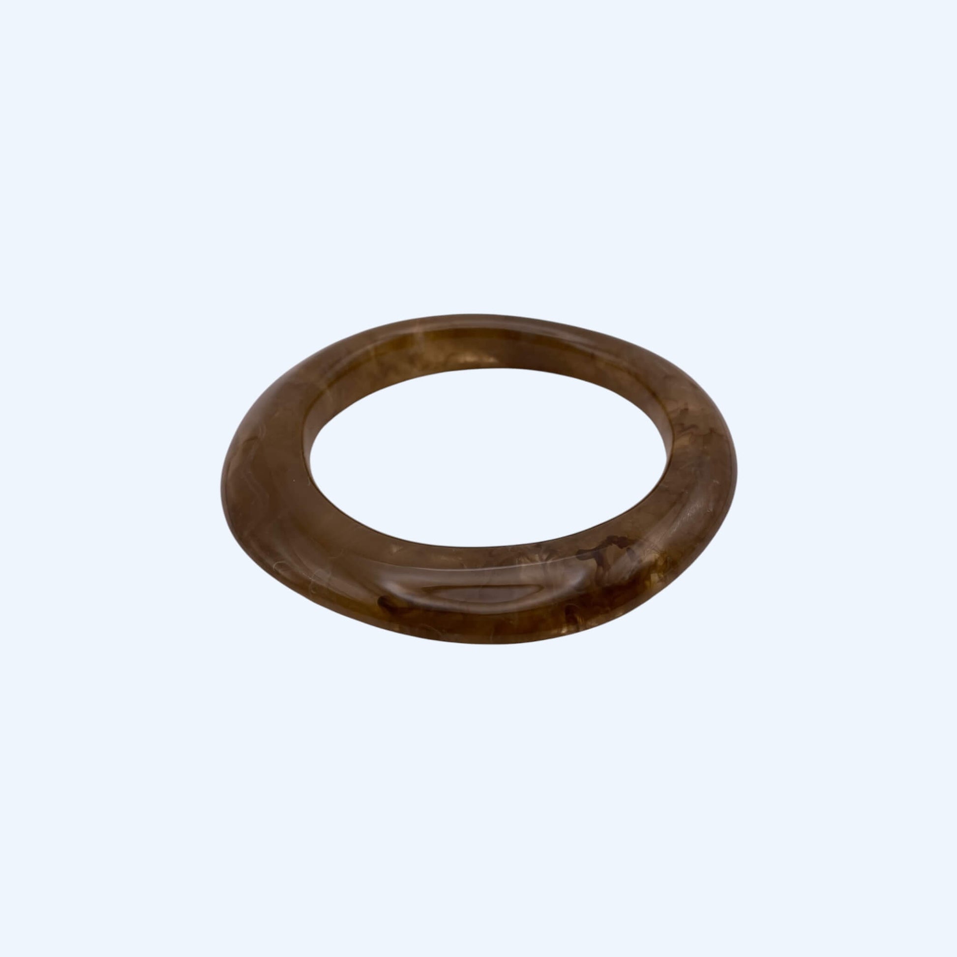 Vista lateral da Pulseira bangle castanha em resina, com acabamento glossy. Pulseira para ser usada sozinha ou em conjunto com outras pulseiras. Pulseira ideal para estilo boho, para estética de verão e da cidade.