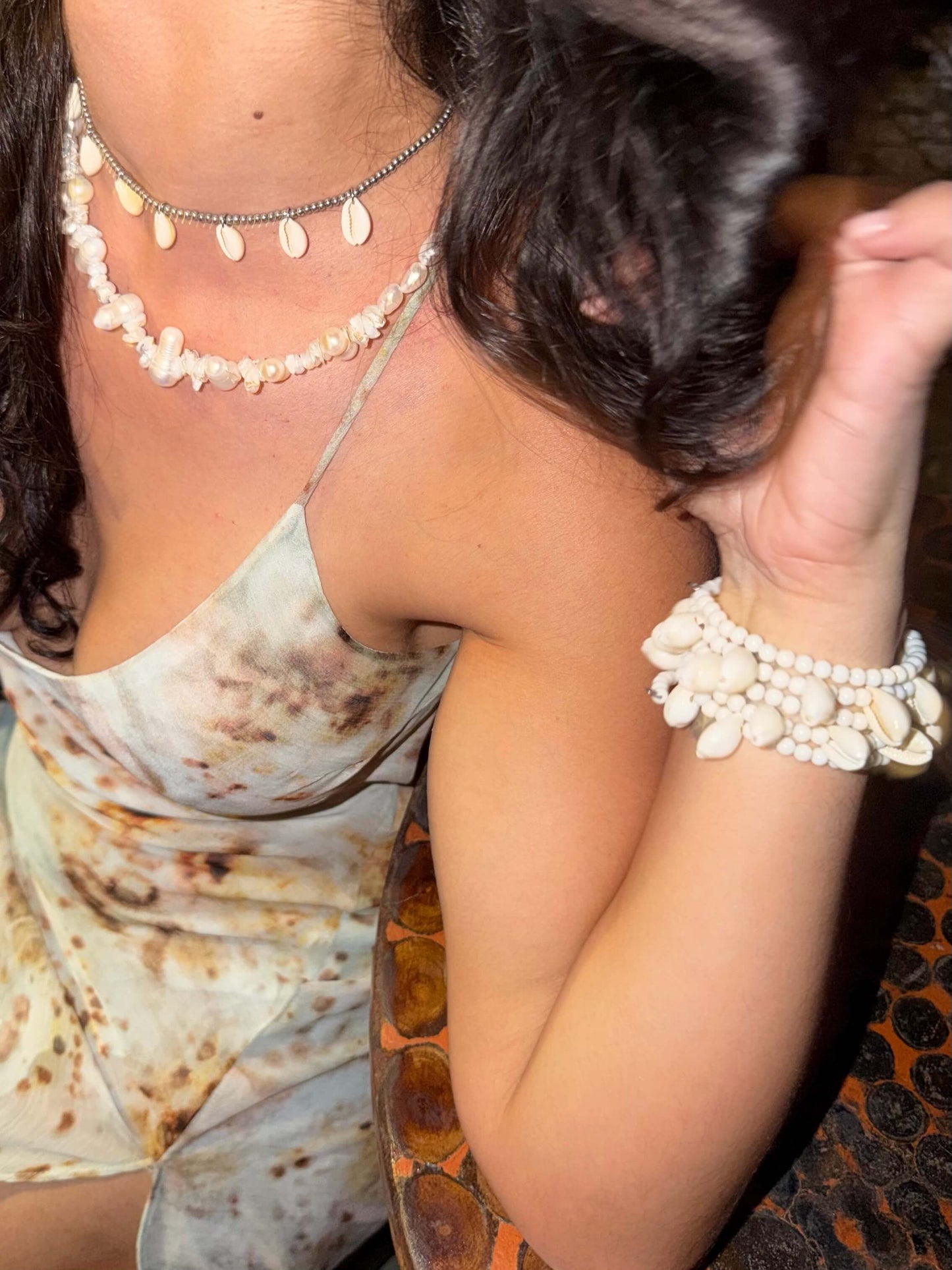 Vista superior da Pulseira ajustável com missangas brancas grandes e búzios. Pulseira leve e descontraída perfeita para looks de verão, na praia e na cidade. Pulseira ideal para festivais e festas.