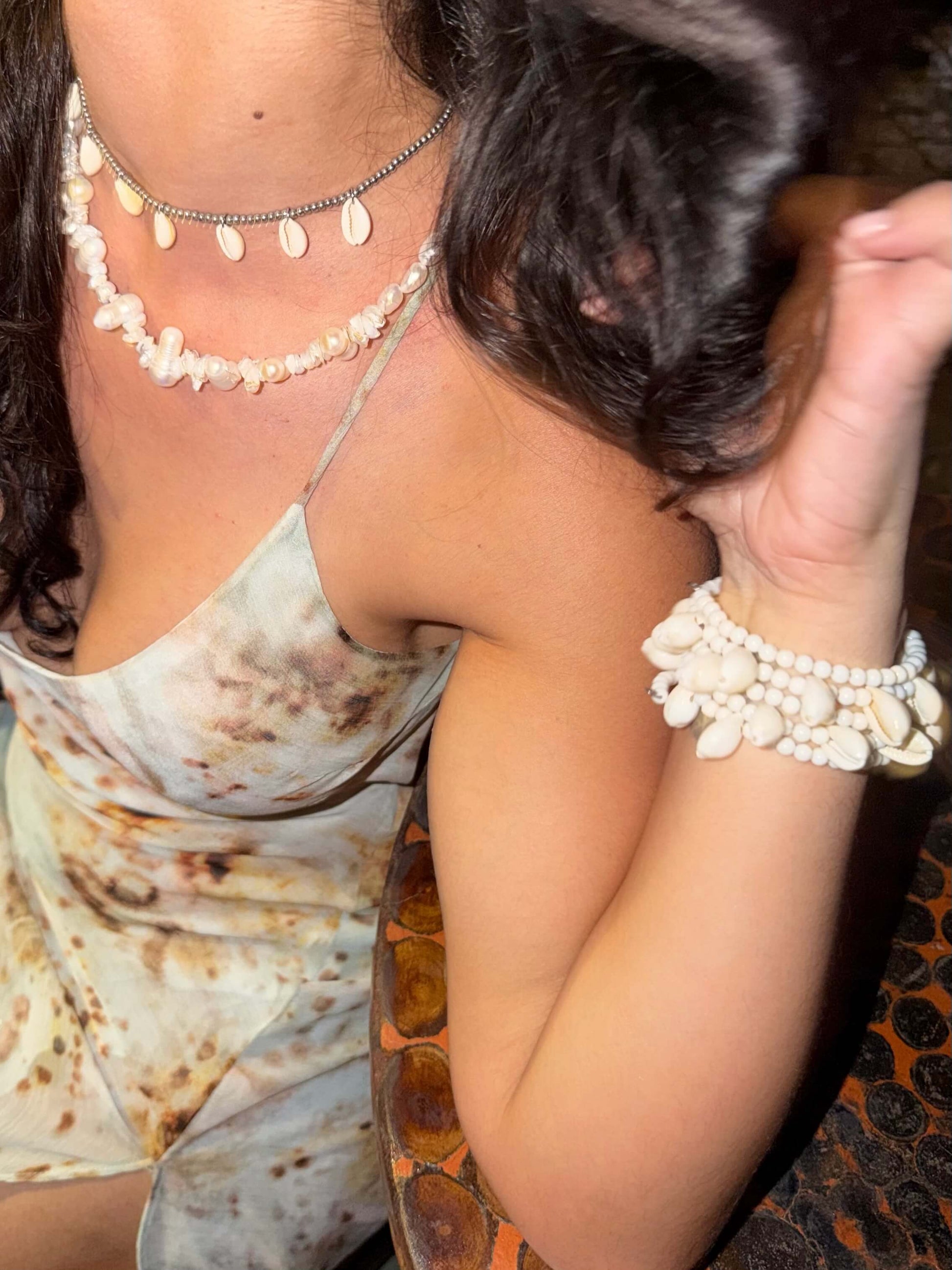 Vista superior da Pulseira ajustável com missangas brancas grandes e búzios. Pulseira leve e descontraída perfeita para looks de verão, na praia e na cidade. Pulseira ideal para festivais e festas.