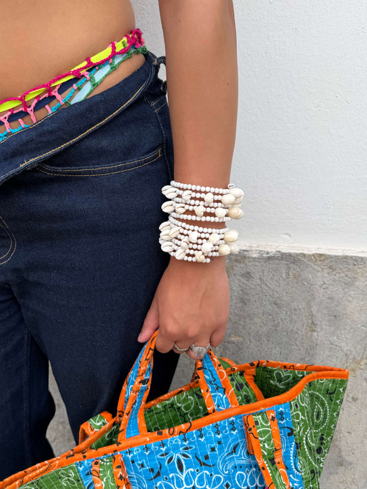 Vista superior da Pulseira ajustável com missangas brancas grandes e búzios. Pulseira leve e descontraída perfeita para looks de verão, na praia e na cidade. Pulseira ideal para festivais e festas.