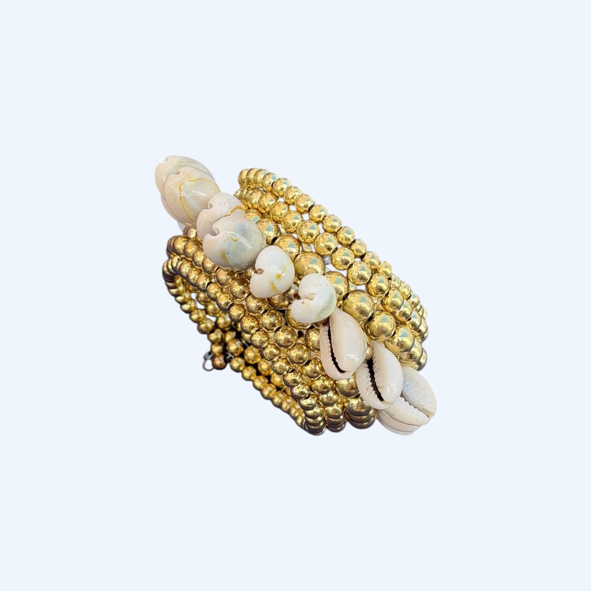 Vista lateral da Pulseira com búzios naturais e esferas douradas metálicas. Esta pulseira tem uma estética mix cool entre um tribal e boho beachy. É uma pulseira com búzios serve aos looks mais basic aos mais irreverentes.