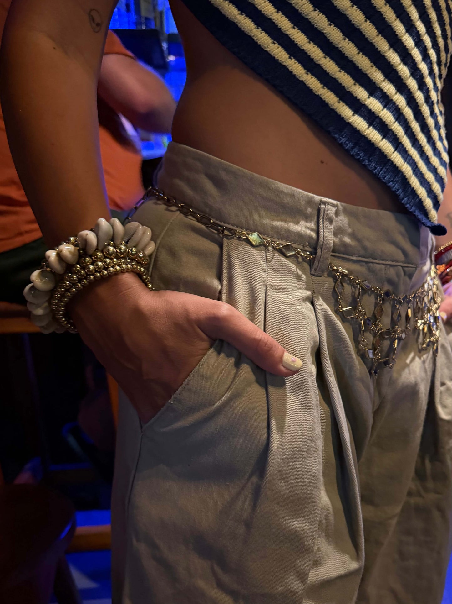 Vista lateral da Pulseira com búzios naturais e esferas douradas metálicas. Esta pulseira tem uma estética mix cool entre um tribal e boho beachy. É uma pulseira com búzios serve aos looks mais basic aos mais irreverentes.