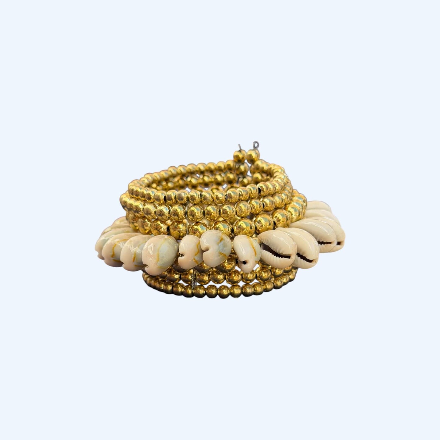 Vista frontal da Pulseira com búzios naturais e esferas douradas metálicas. Esta pulseira tem uma estética mix cool entre um tribal e boho beachy. É uma pulseira com búzios serve aos looks mais basic aos mais irreverentes.