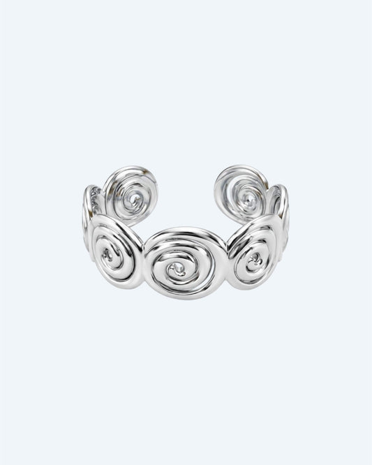 Vista frontal da Pulseira prateada rígida mas ajustável em aço inoxidável, composta por espirais recortadas e acabamento polido. Esta pulseira é ideal para looks boho ou urbanos, também para mais artisticos e de quem pretende ser simples com um detalhe ou para quem pretende juntar a um estilo bold.