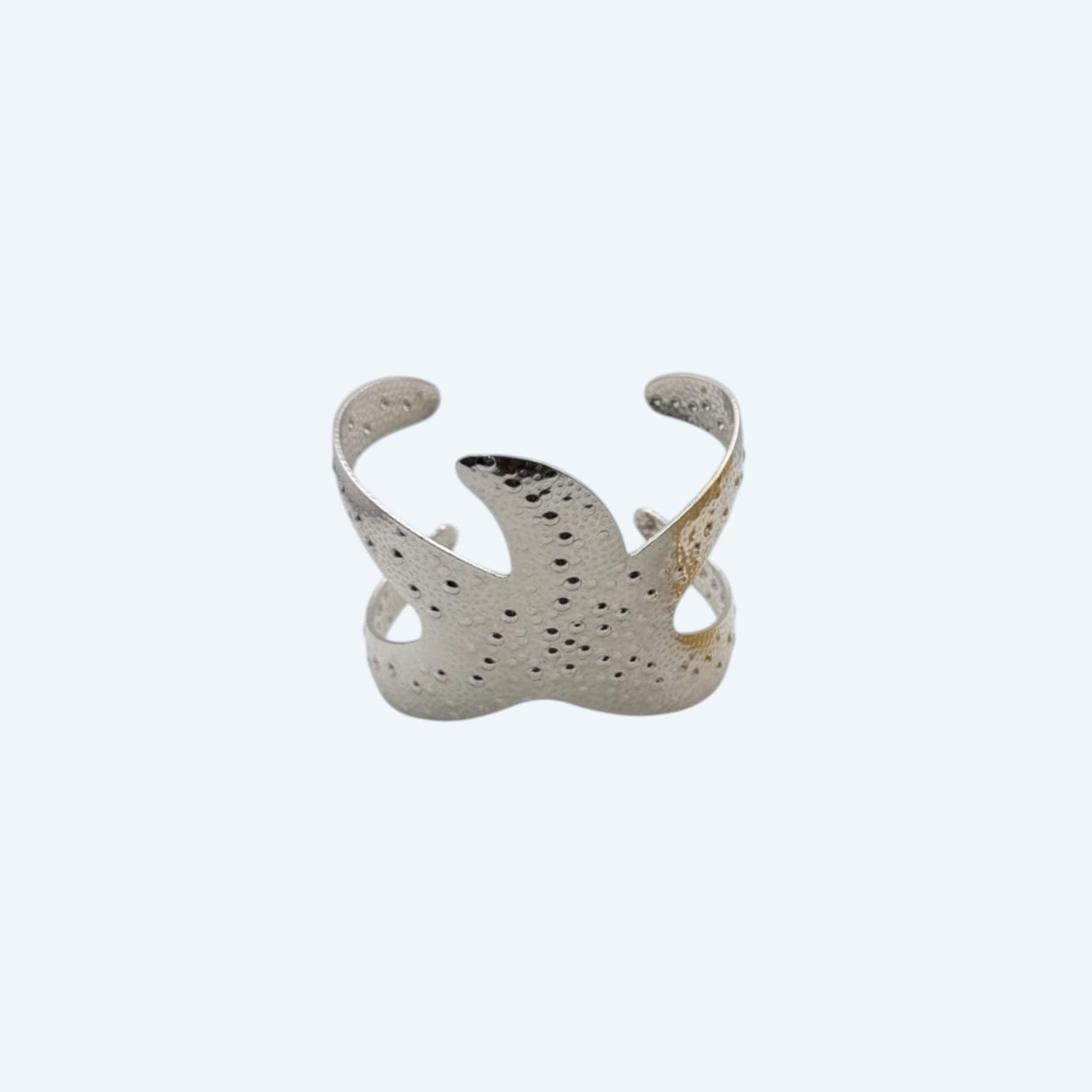 Vista superior da pulseira larga prateada, com formato de estrela do mar grande, em aço inoxidável de bracelete ajustável. Pulseira de verão com beach energy para looks de verão, looks de festas, sunsets, festivais ou para o dia a dia.